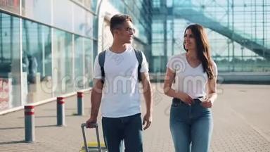 幸福的年轻夫妇带着行李去机场或火车站附近。 旅游、度假、度假的概念